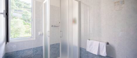 Un baño con ducha acristalada, inodoro y lavamanos.