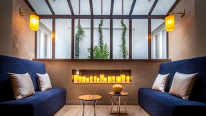 Un espace de détente moderne avec deux canapés bleus, un plancher en bois et un luminaire fixé au mur.