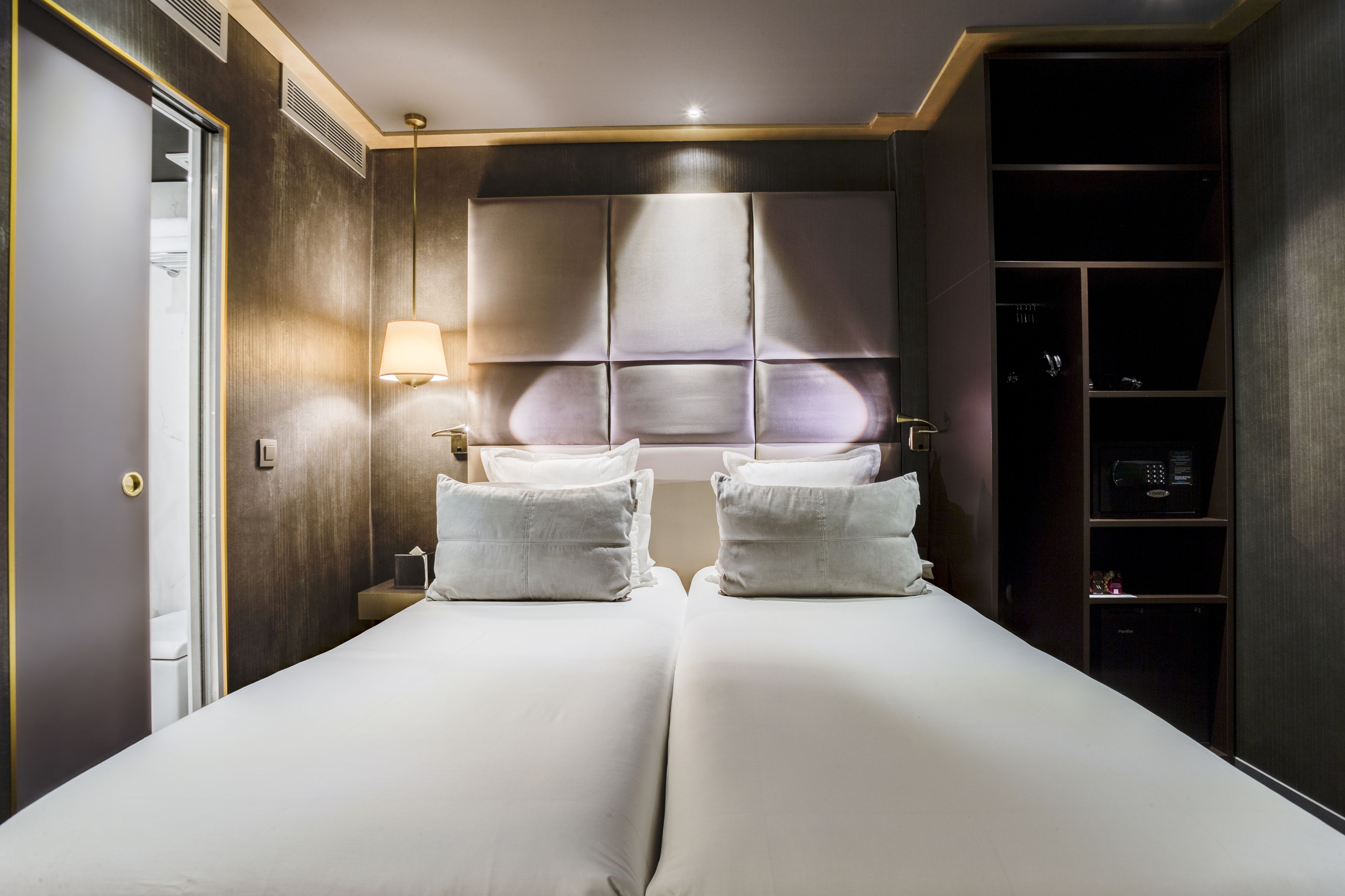 Una habitación de hotel con una cama grande, dos mesitas de noche, un armario y una ventana con persianas.