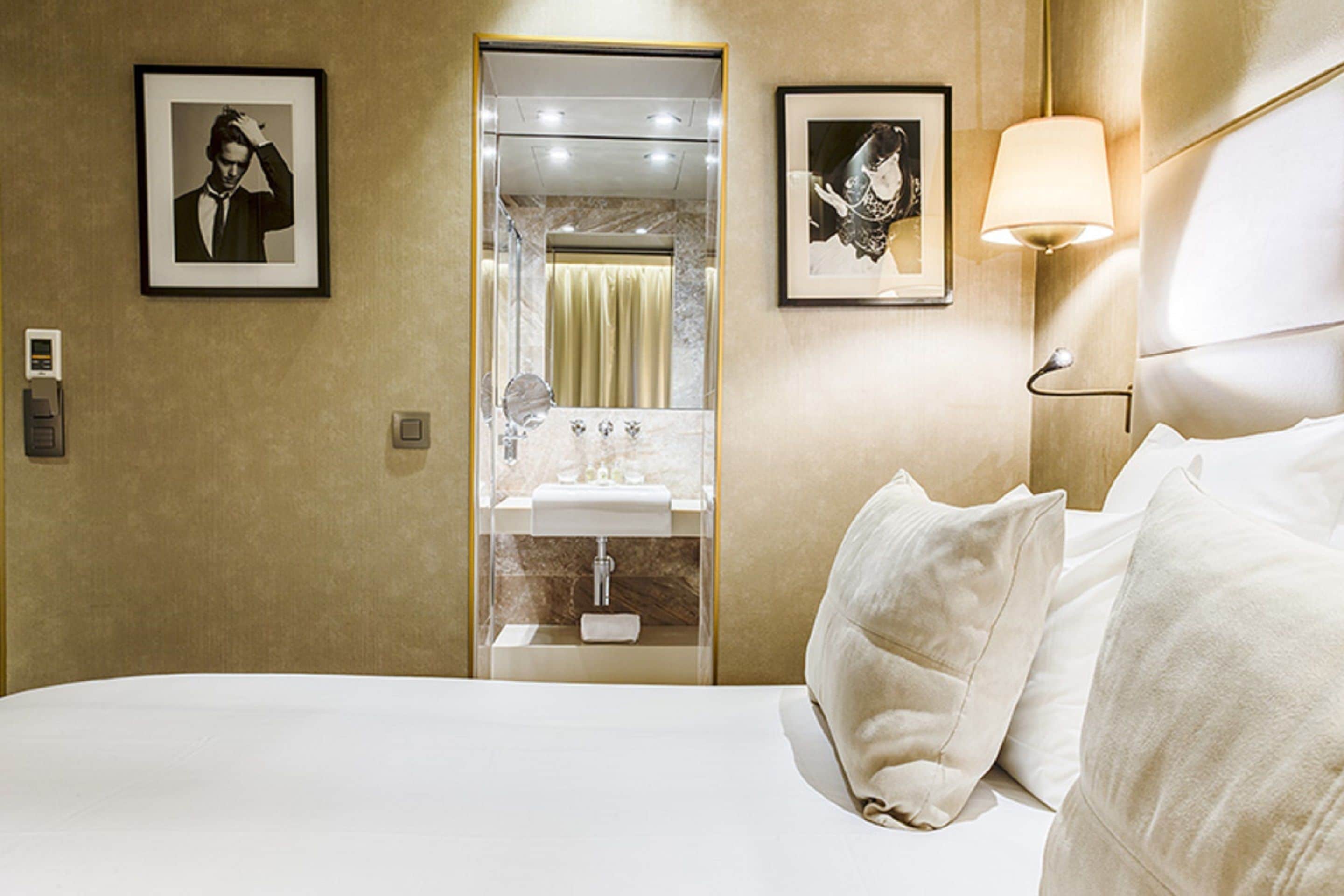 Een hotelkamer met een bed, een badkamer met een spiegel en afbeeldingen in lijsten aan de muur.