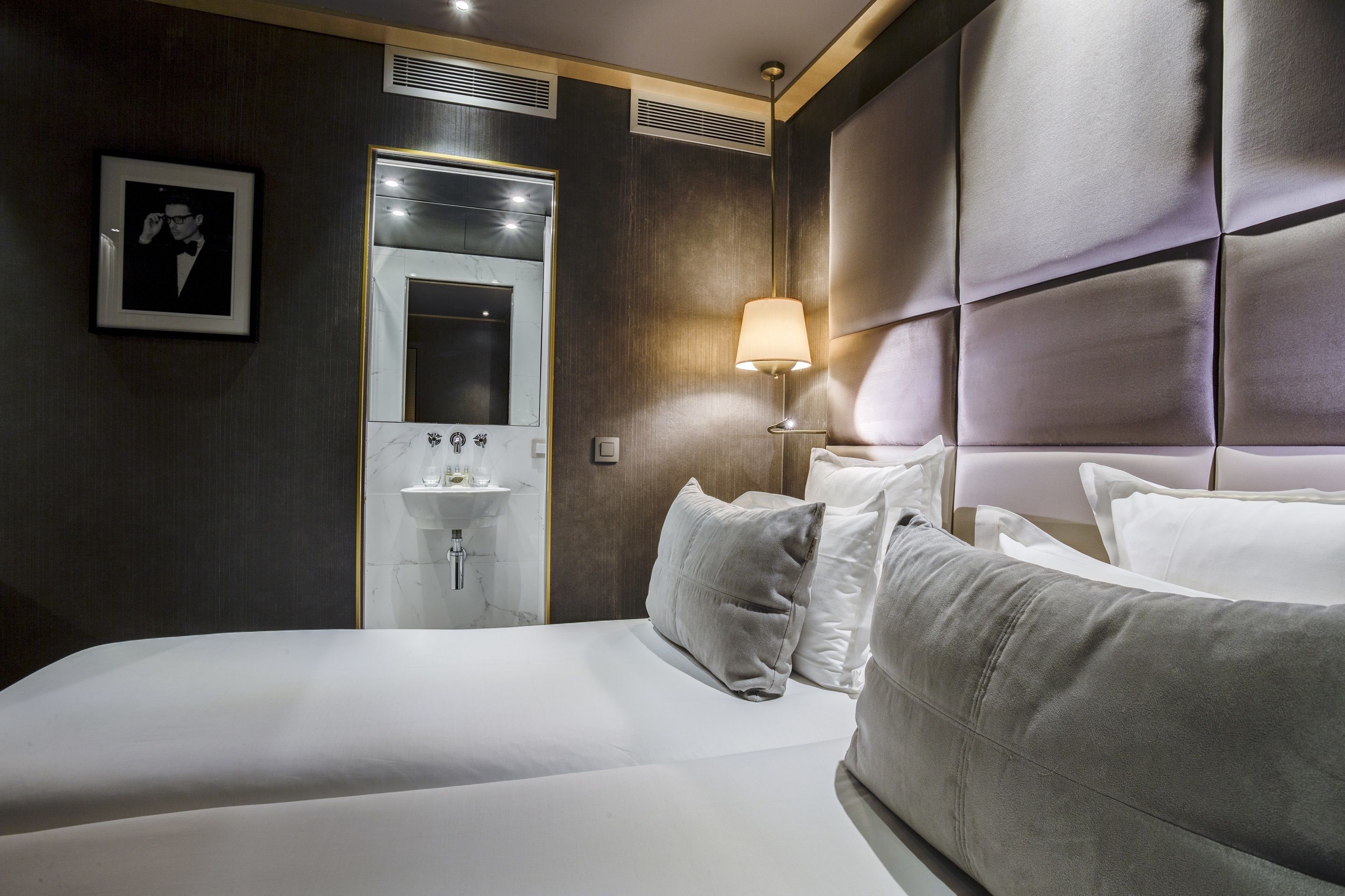 Una habitación de hotel con una cama grande, una lámpara de noche, un espejo y un cuadro en la pared.