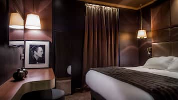 Una habitación de hotel con una cama, un escritorio, un espejo y un cuadro en la pared.