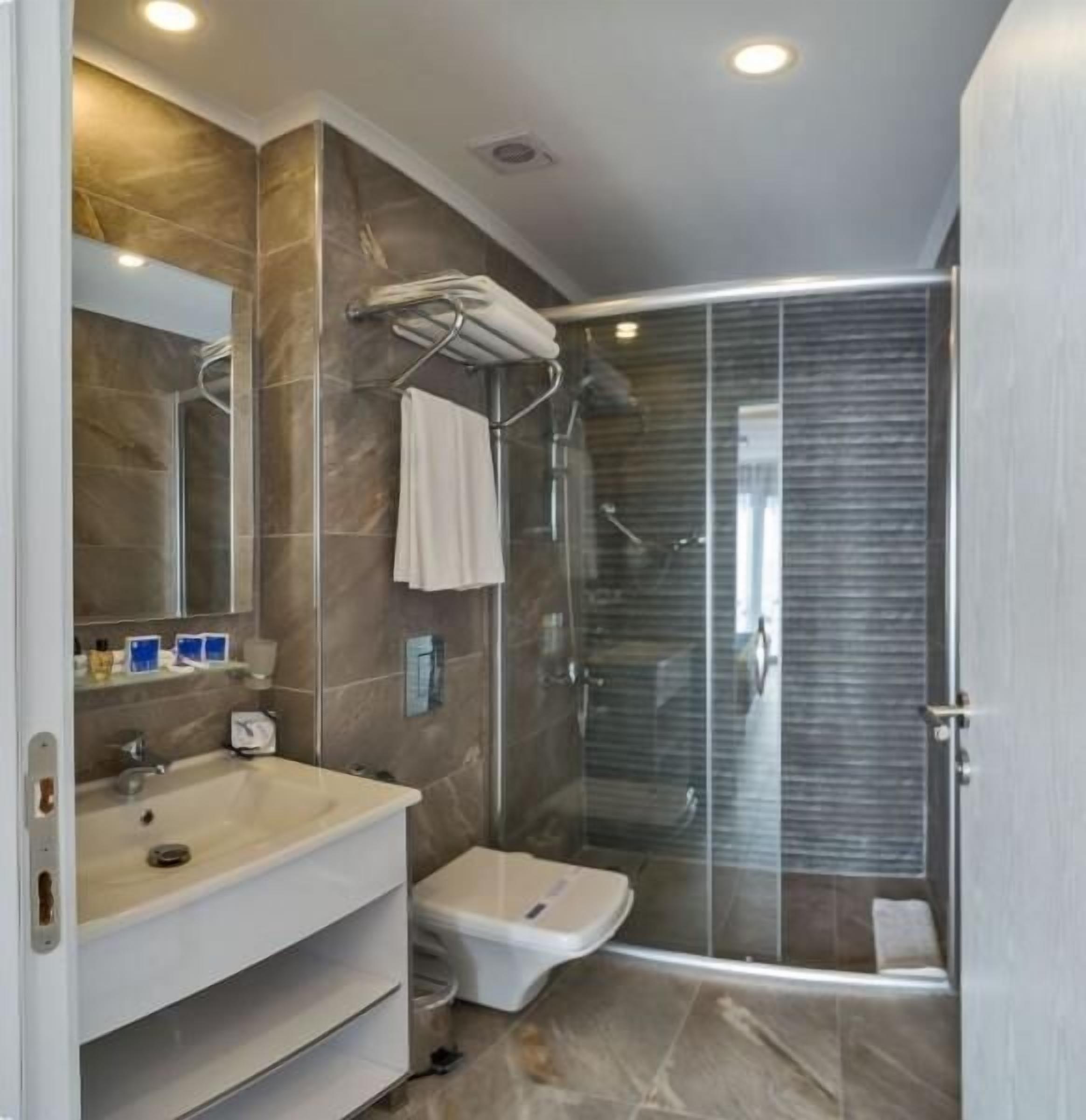 A modern bathroom with a shower, sink, and toilet.