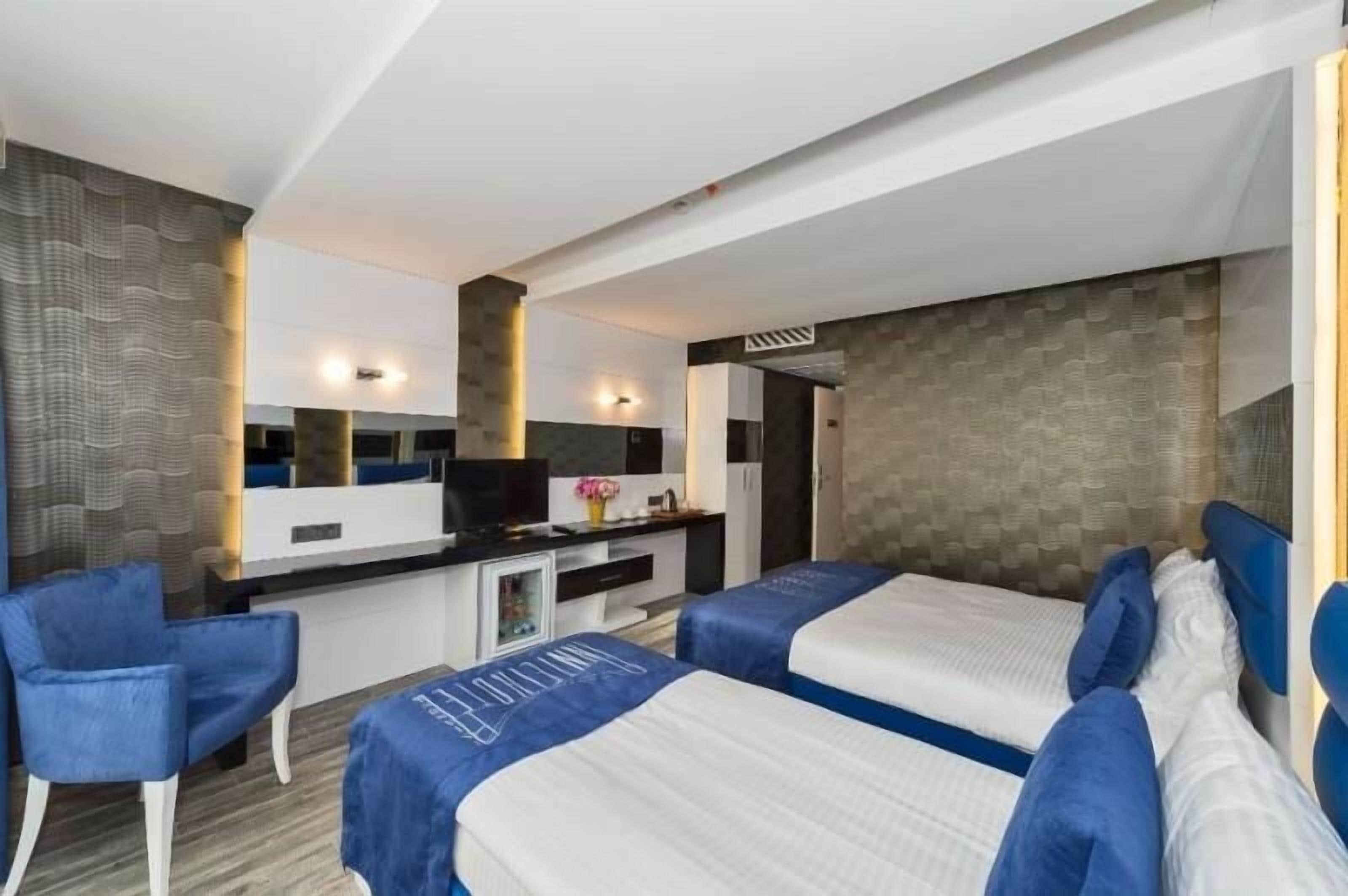 Una habitación de hotel con dos camas, un escritorio, una silla y un televisor.