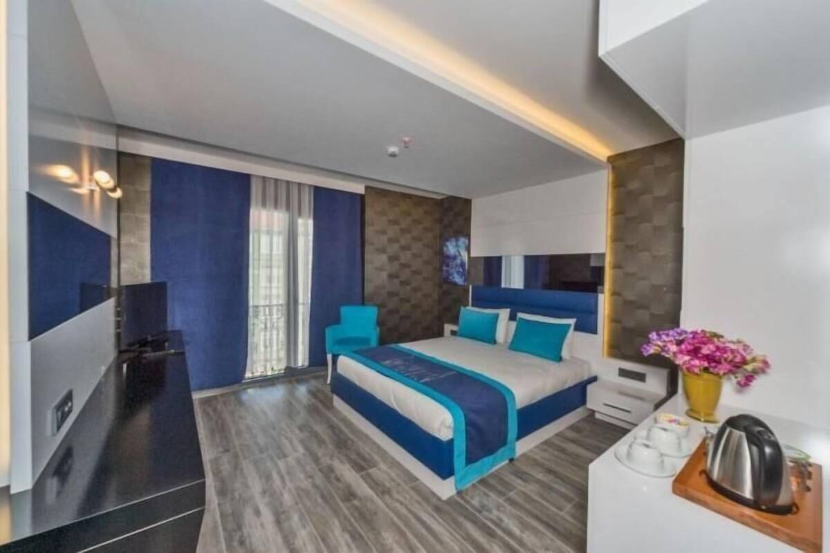 Une chambre d’hôtel moderne avec un grand lit, un petit coin salon, une table basse et un vase de fleurs.