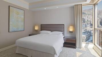 A hotel room with a large bed, two bedside lamps, a city view, and a patterned carpet.
