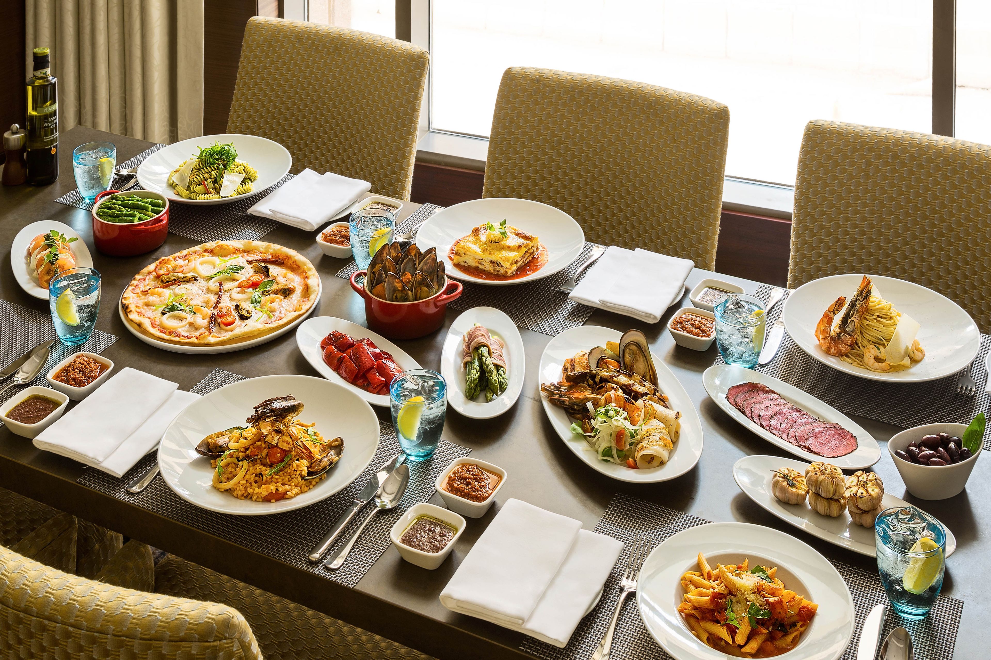 A dining table with various dishes, including seafood, pasta, and vegetables, set for a meal.
