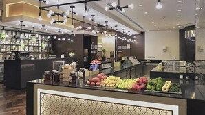 A modern hotel lobby with a central counter displaying fresh produce, a bar area with shelves of bottles, and a ceiling with multiple light fixtures. - Jabal Omar Hyatt Regency Makkah (Makkah)