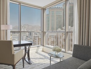 Habitación de hotel moderna con un ventanal grande que ofrece vistas a la ciudad, un sofá cómodo, una mesita y una lámpara.