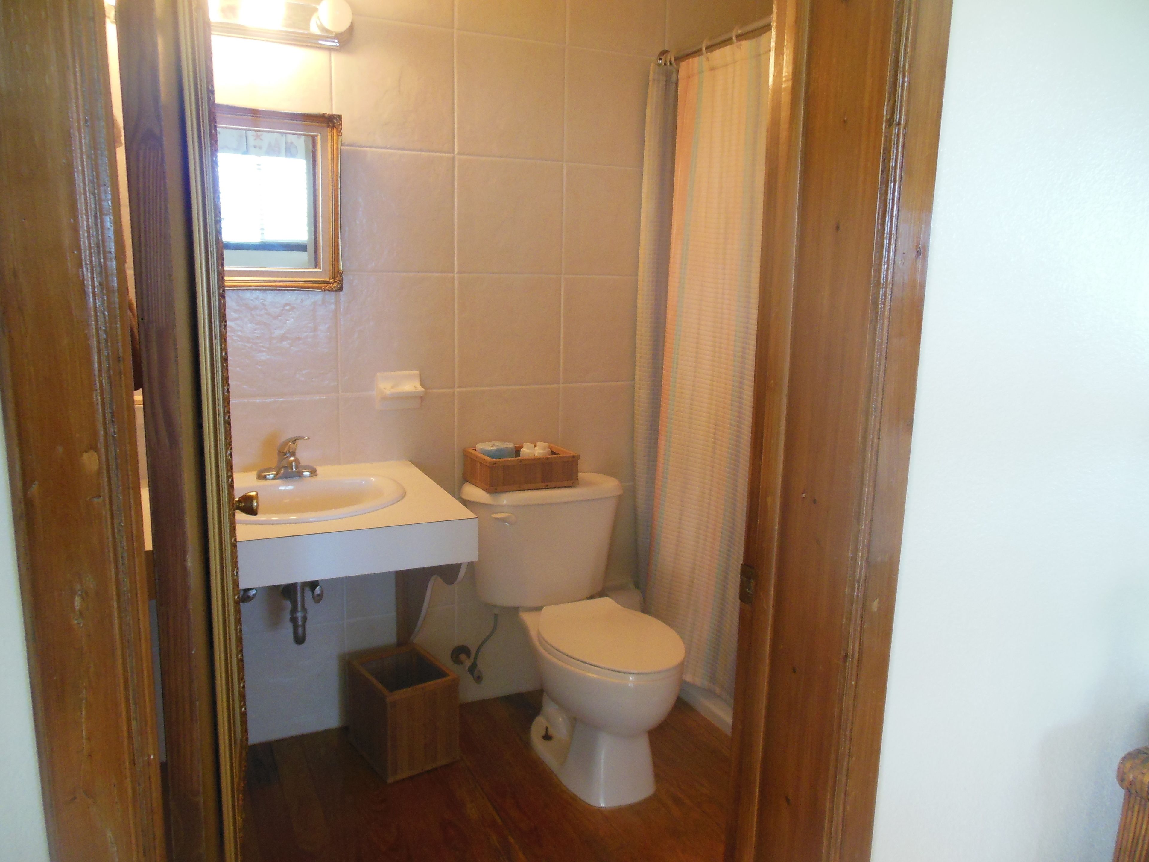 A small bathroom with a sink, toilet, and a wooden box on the floor.