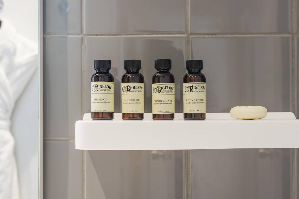 Four bottles of Bigelow products on a white shelf against a tiled wall.