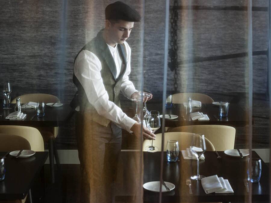 A waiter serving wine at a restaurant table.