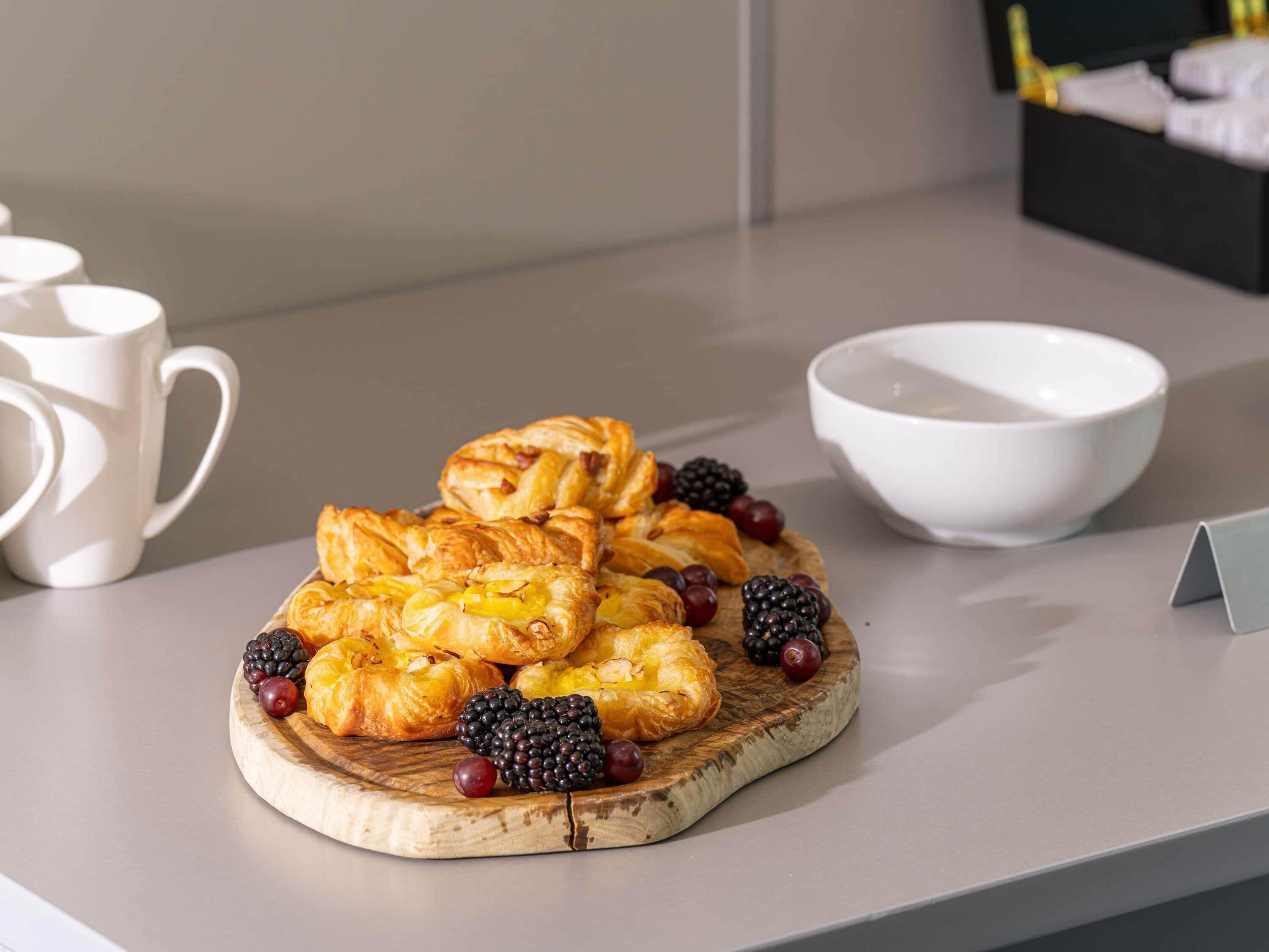 Uma tábua de madeira com doces e frutas vermelhas sobre uma mesa.