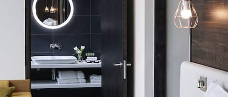 A modern bathroom with a round mirror, white sink, and a towel rack.