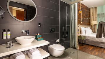 A modern bathroom with a round mirror, white sink, and a glass-enclosed shower.