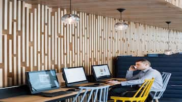 A modern workspace with wooden slats on the wall, two desks with computers, and a person using a mobile device.