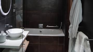 A modern bathroom with a large bathtub, a round mirror, and a white sink.