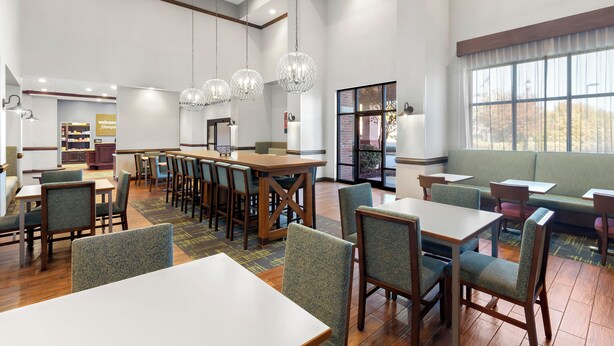 Un restaurant spacieux avec de hauts plafonds, de magnifiques lustres en cristal et différents types de sièges, notamment des tables et des banquettes.