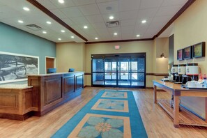 A reception area with a wooden counter, a blue carpet with floral patterns, and a coffee station.