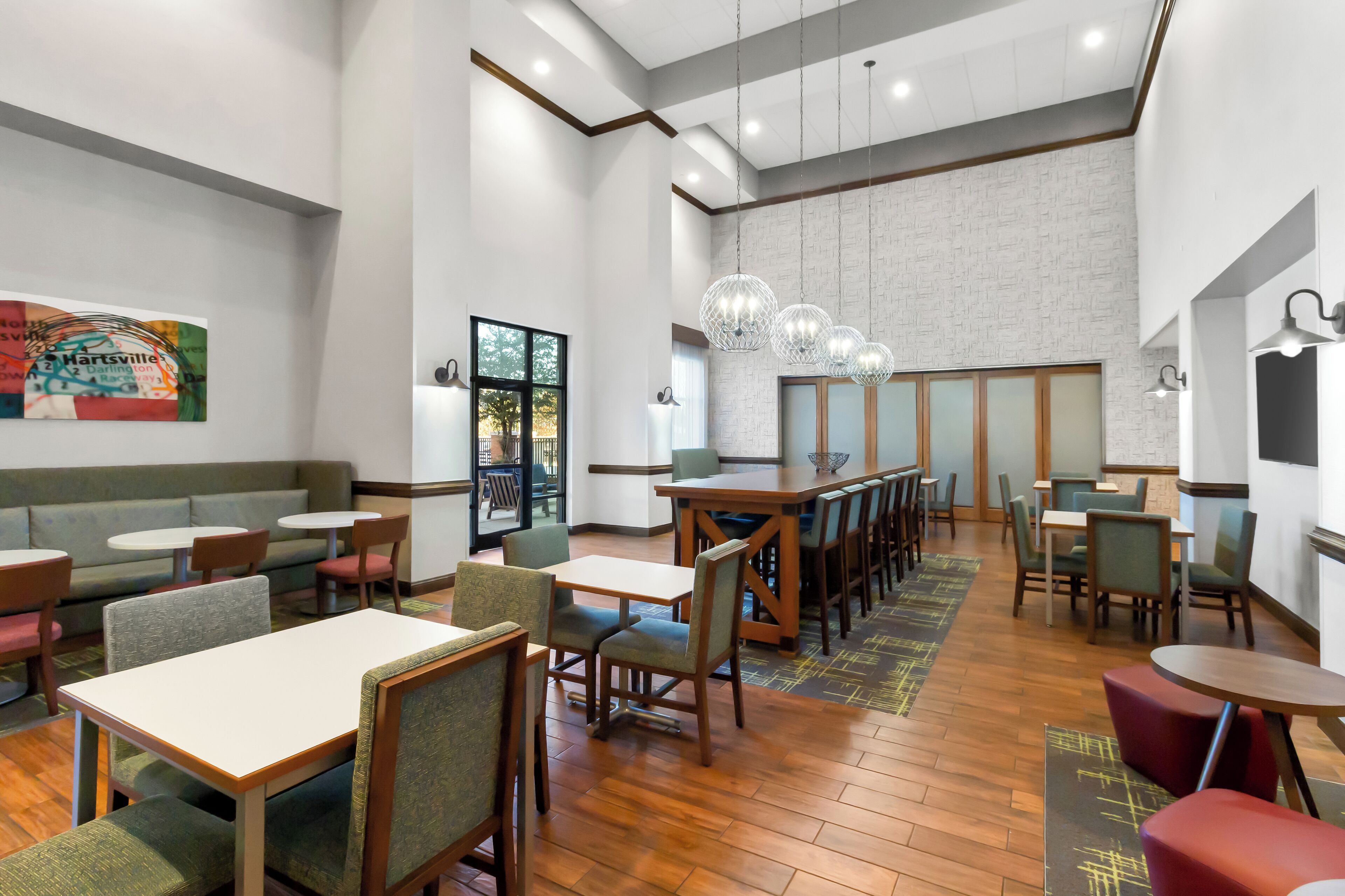 A spacious restaurant with high ceilings, wooden flooring, and a variety of seating options including tables and booths.
