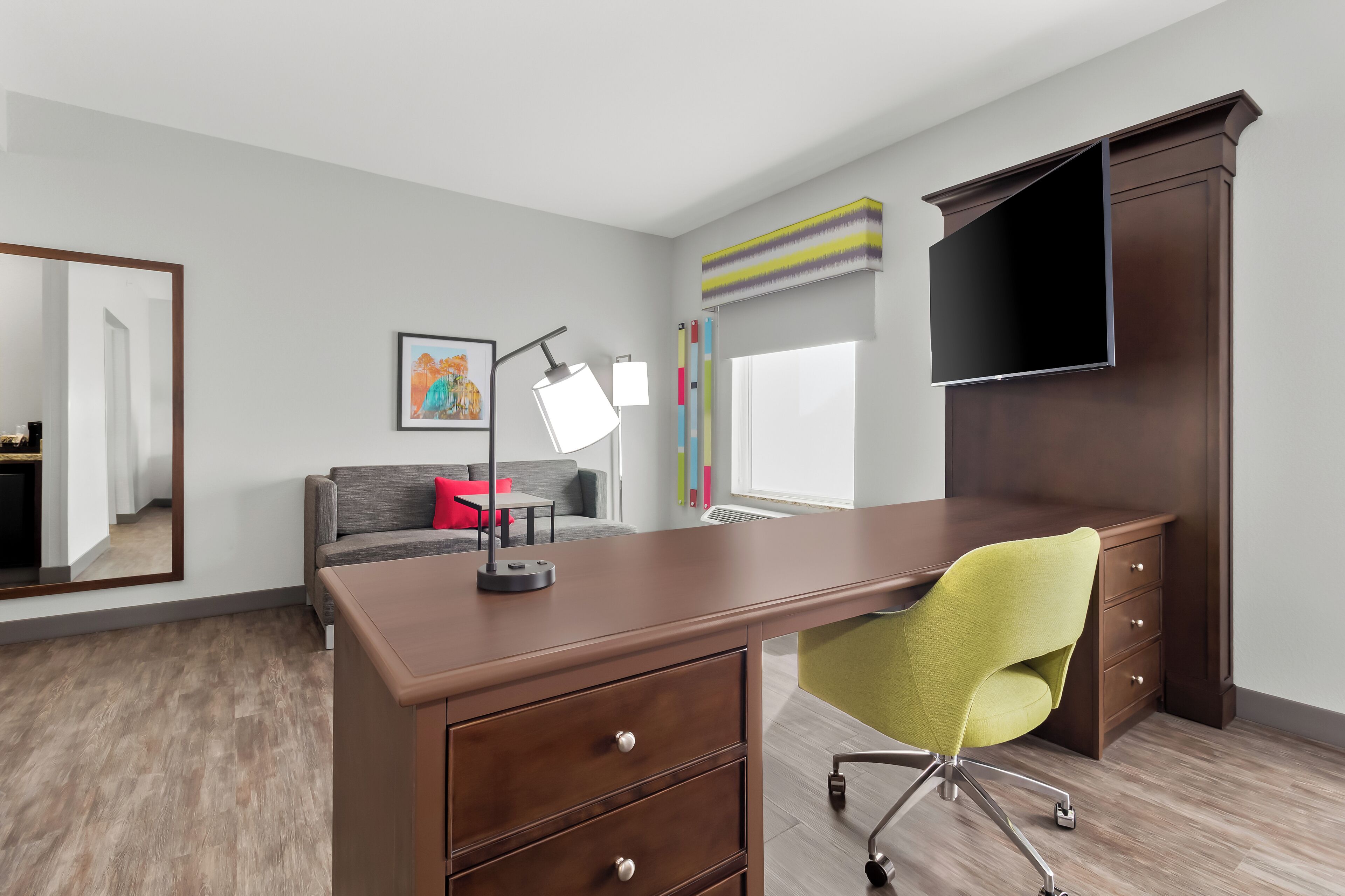 A modern office space with a desk, chair, and a large mirror.