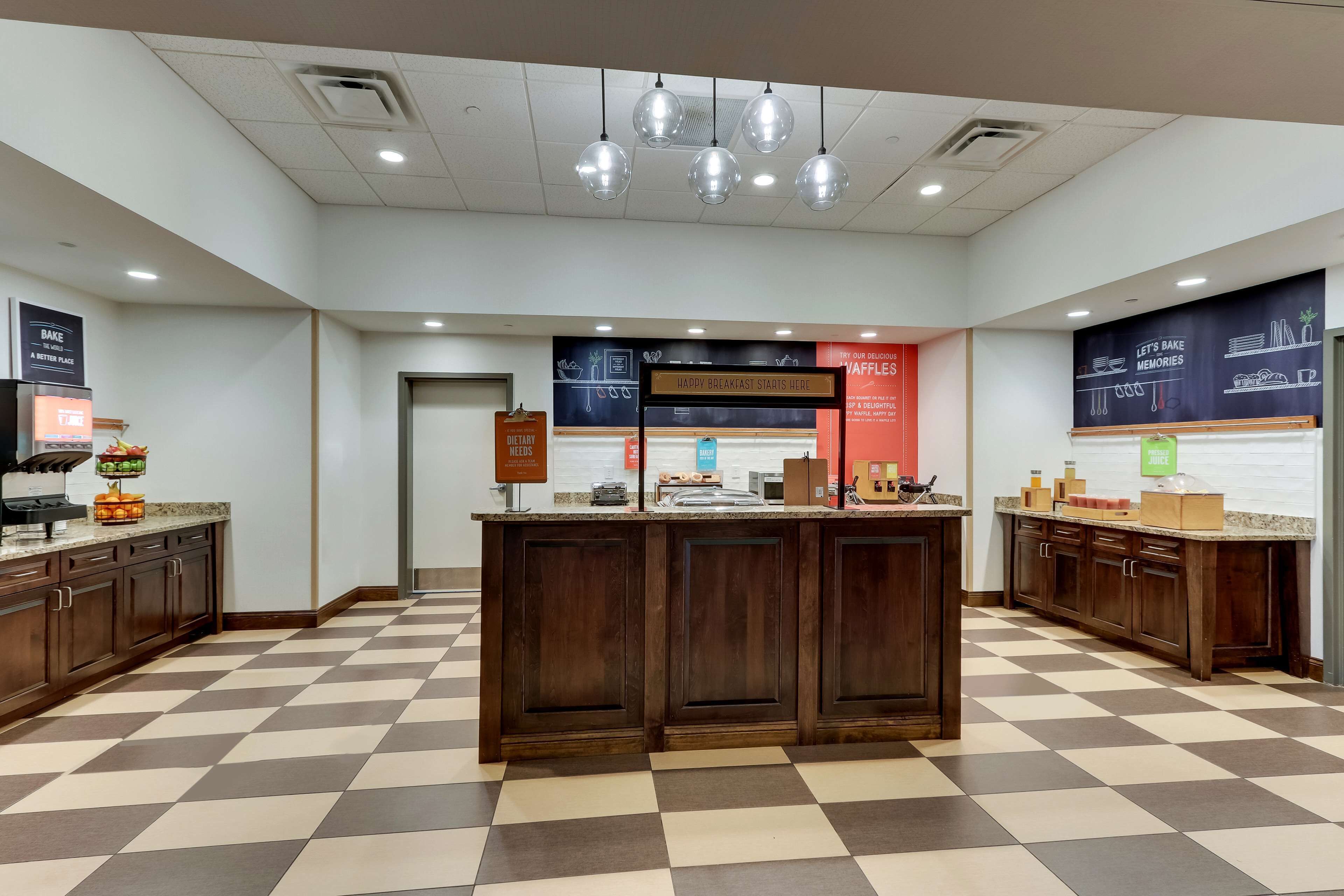 A bakery counter with a checkered floor, a sign that says "Happy Breakfast Starts Here," and a sign indicating the location of the bakery.