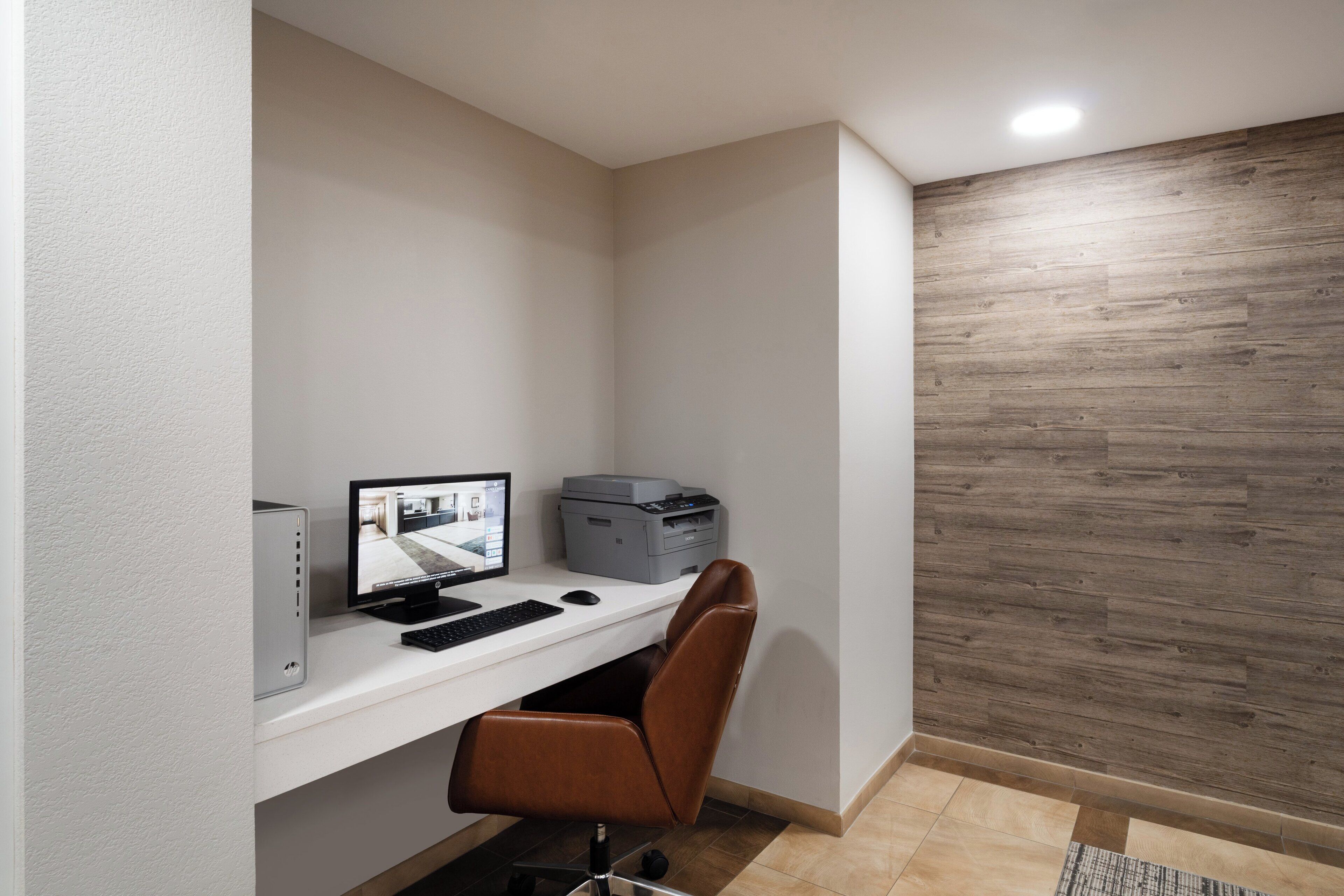 Um espaço de escritório em casa com mesa, computador, impressora e cadeira.