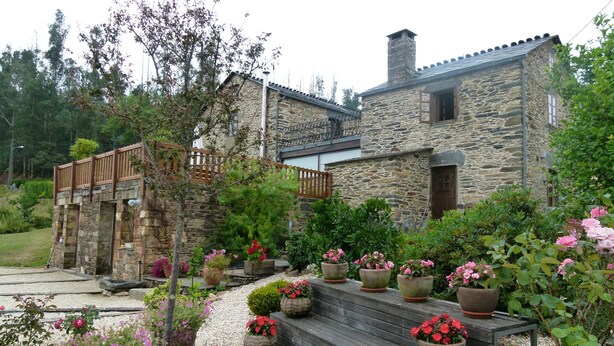 A stone house with a wooden deck and potted plants. - Casa Piñeiro (Monfero)