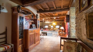 A rustic interior with wooden beams, stone walls, a wooden cabinet, and a cozy seating area. - Casa Piñeiro (Monfero)