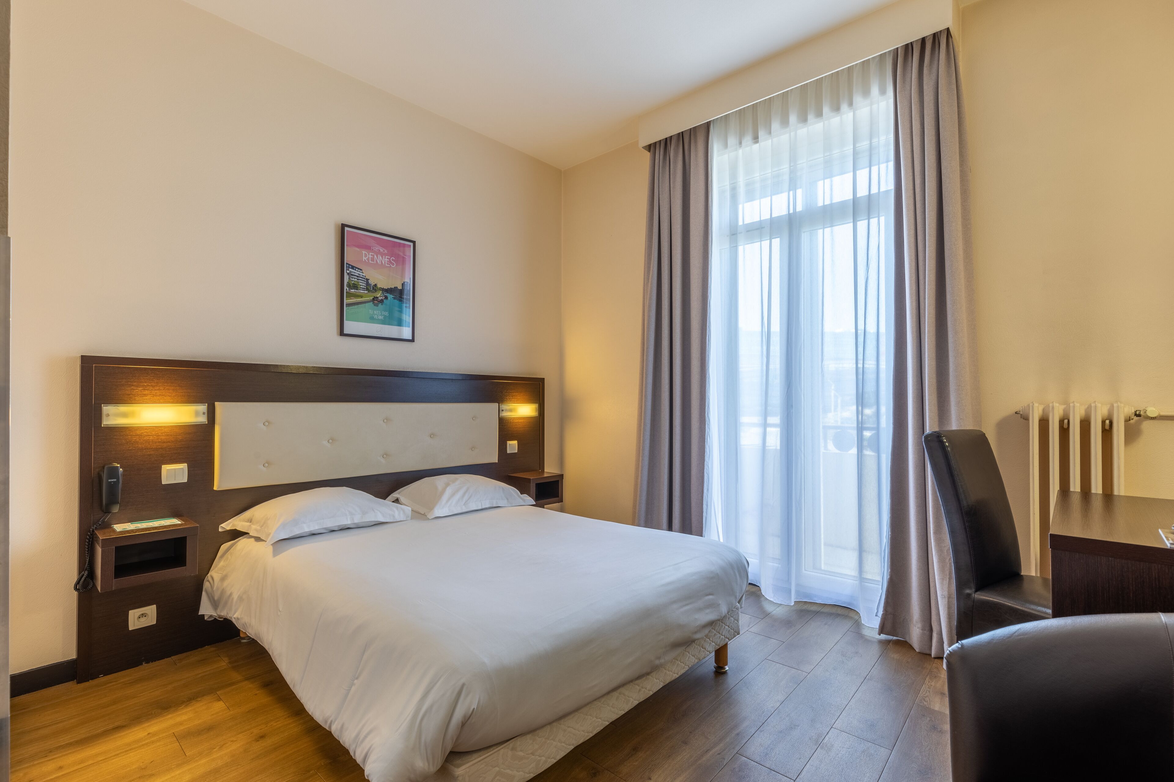 Quarto de hotel com uma cama grande, mesas de cabeceira, escrivaninha e uma cadeira.