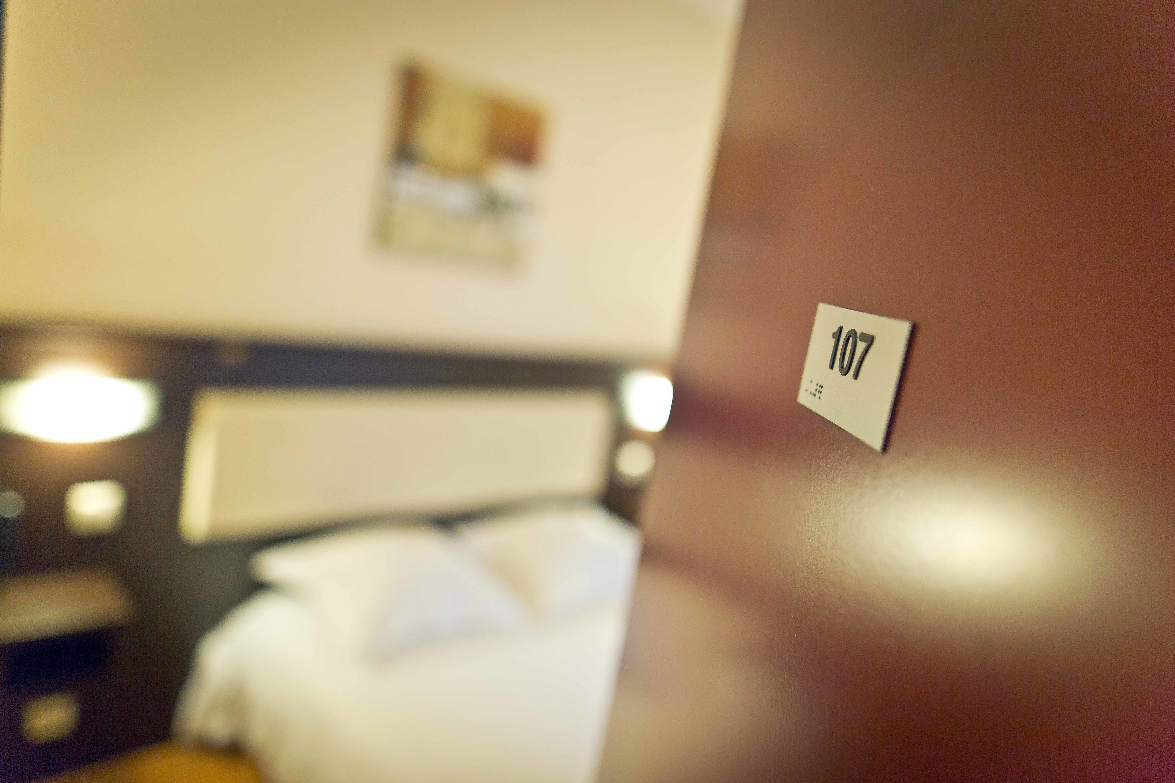 Gros plan sur une plaque indiquant le numéro de chambre, « 107 », sur un mur.