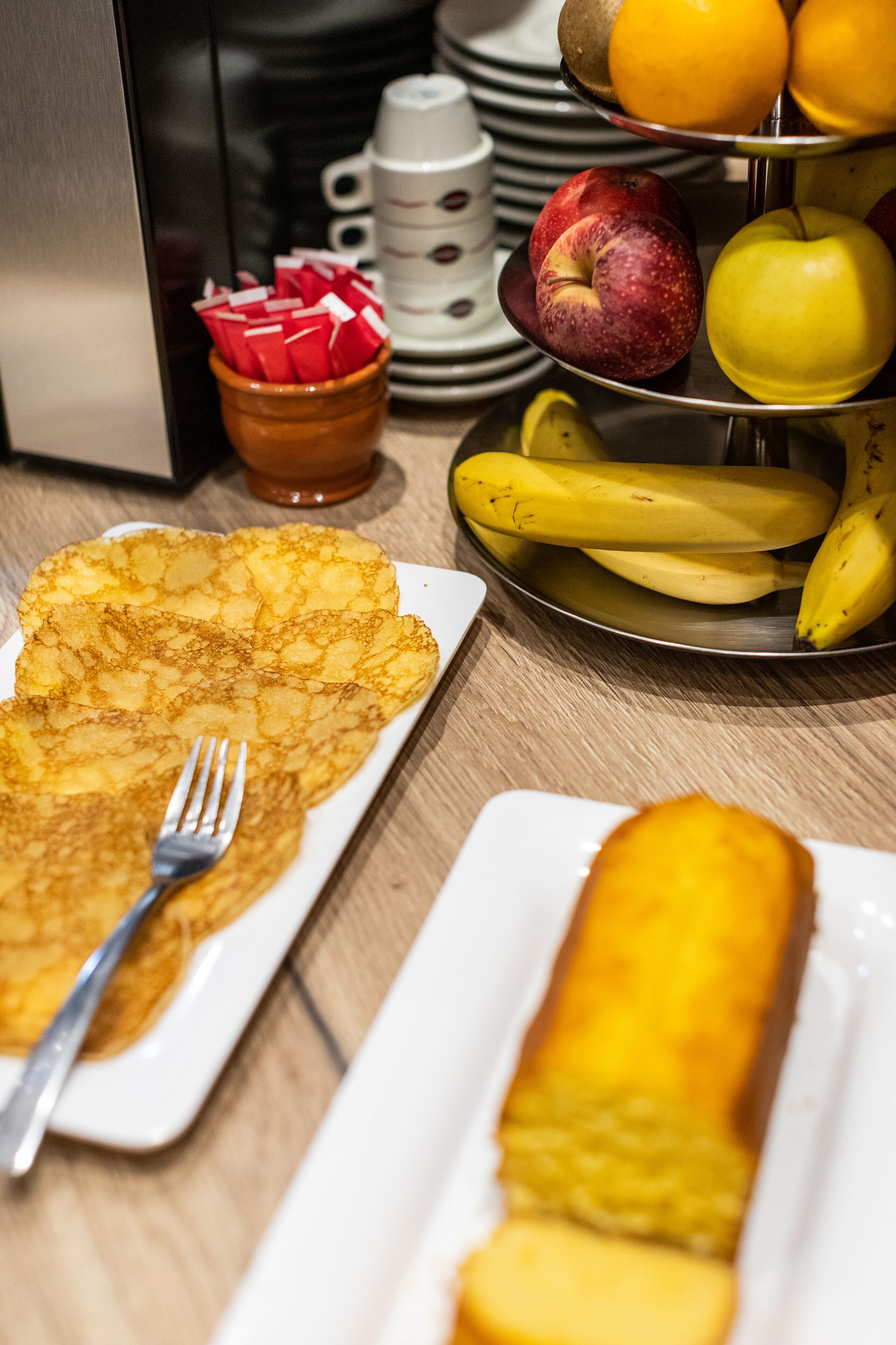 A breakfast setting with pancakes, a banana, and a plate of fruit.