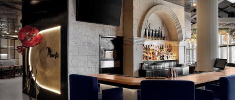 A modern bar area with a marble countertop, blue bar stools, and a wine display.