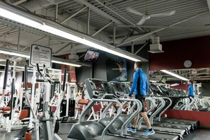 A gym with treadmills, weight machines, and a large mirror. - Hôtel MOCO Valleyfield (Salaberry De Valleyfield)