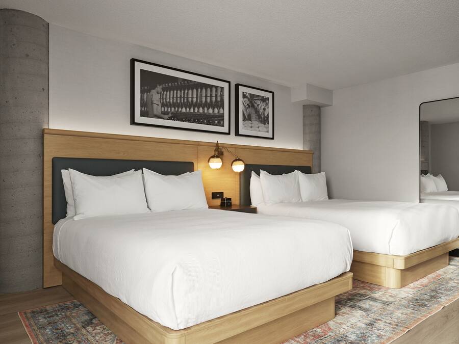 A hotel room with a large bed, a bedside table, a lamp, and two framed pictures on the wall.