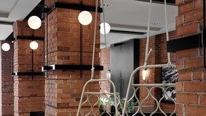A modern interior with hanging chairs, brick walls, and pendant lighting. - Hôtel MOCO Valleyfield (Salaberry De Valleyfield)