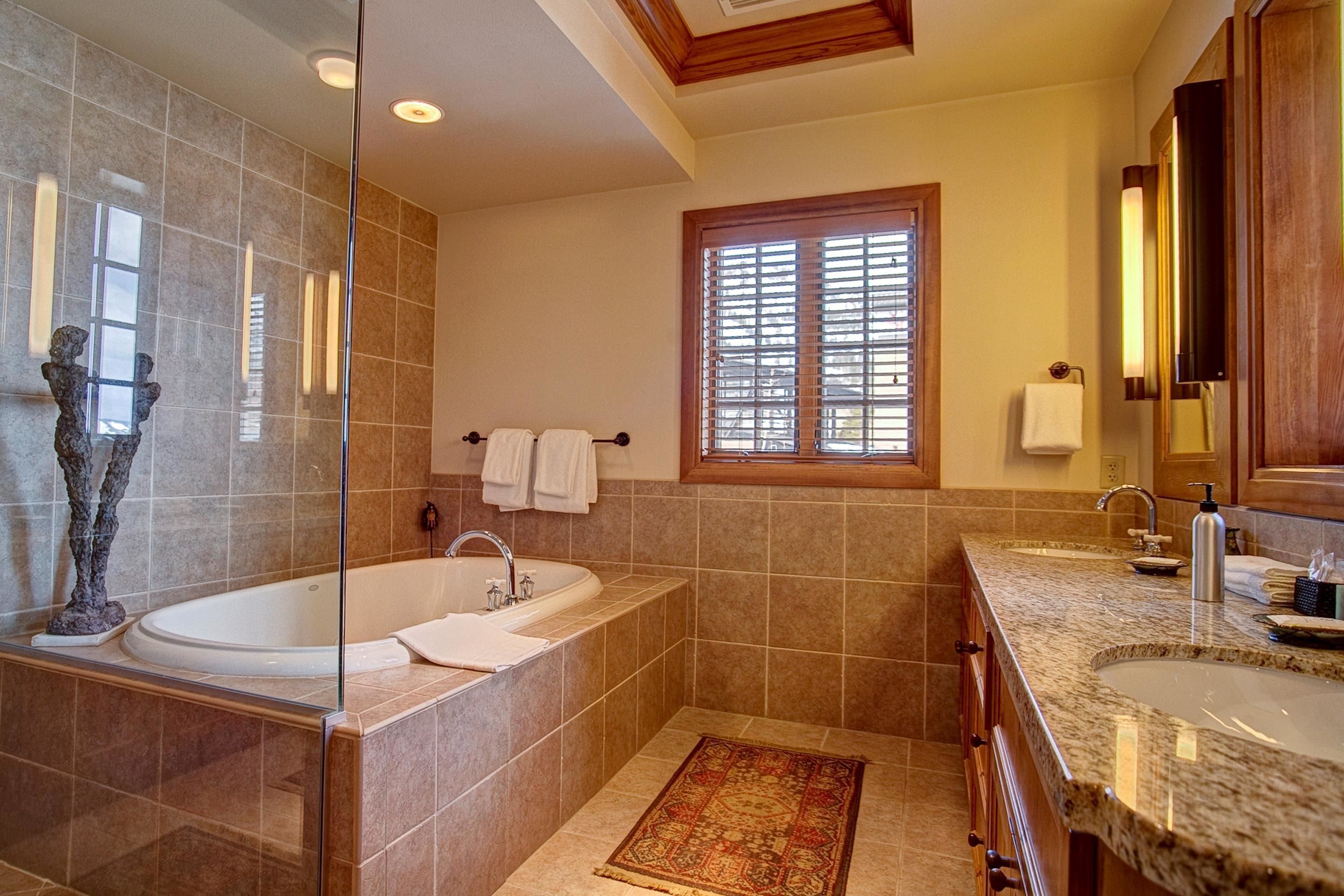 Une salle de bain moderne avec une baignoire sur pieds, deux vasques et une grande fenêtre.