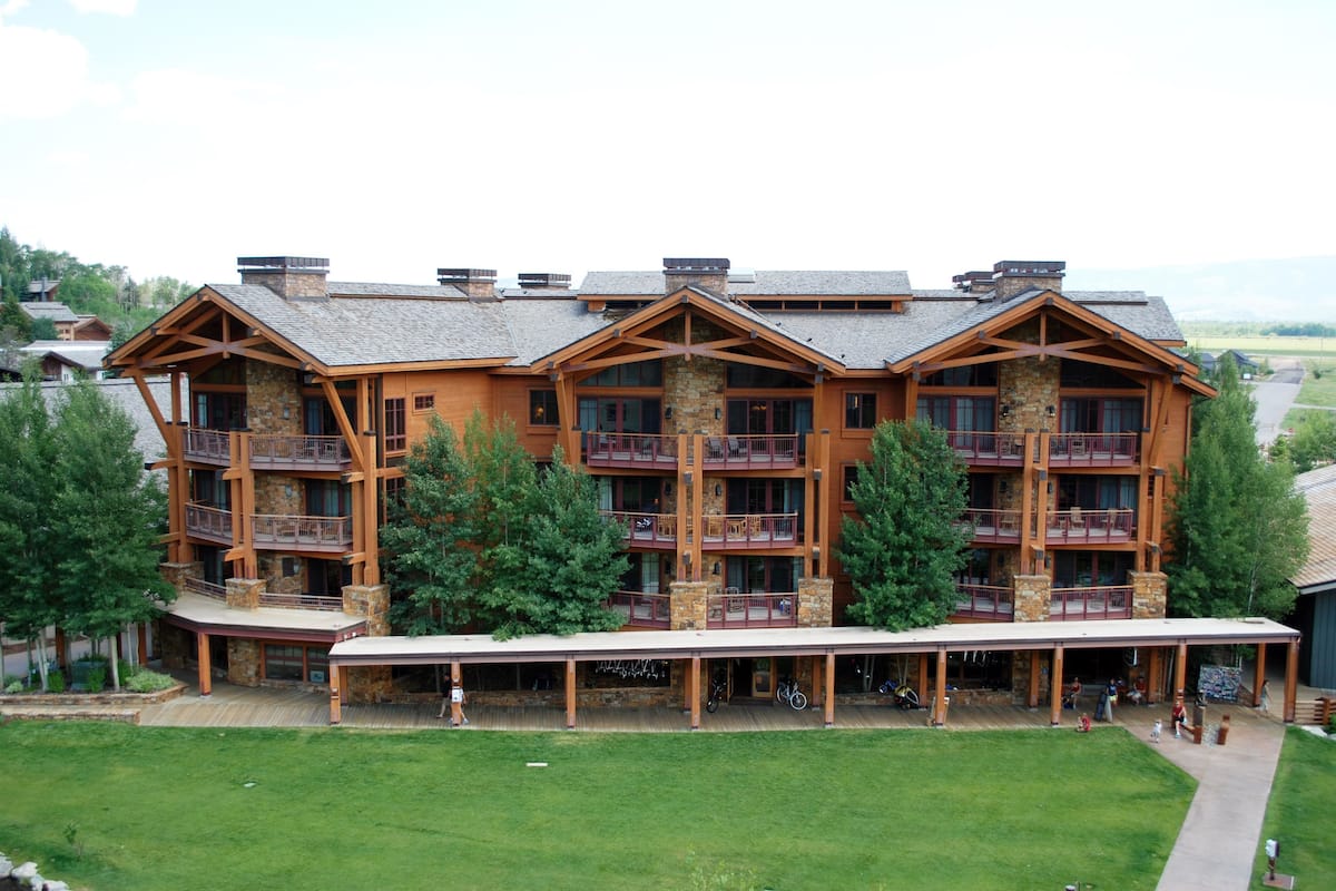 A multi-story lodge with balconies, a covered patio, and a stone facade.