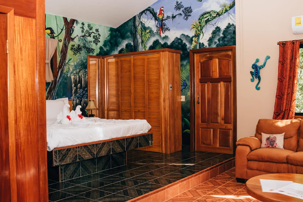 Quarto com cama, guarda-roupa, uma cadeira e um mural na parede.