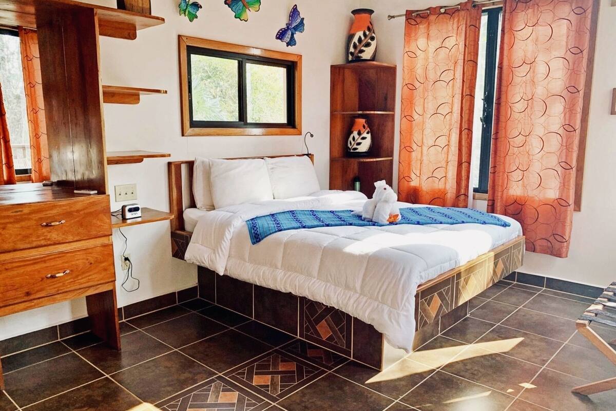 Quarto com cama, cómoda de madeira, estantes e janela.