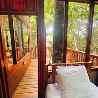 Una terraza de madera con una cama, una mesita de noche y una lámpara.