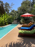 Una piscina al aire libre, sombrillas, sillones reclinables de piscina