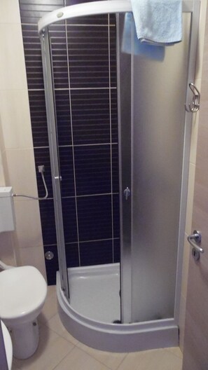 A bathroom with a shower enclosure, a toilet, and a towel hanging on the shower door. - Villa Sara (Makarska)