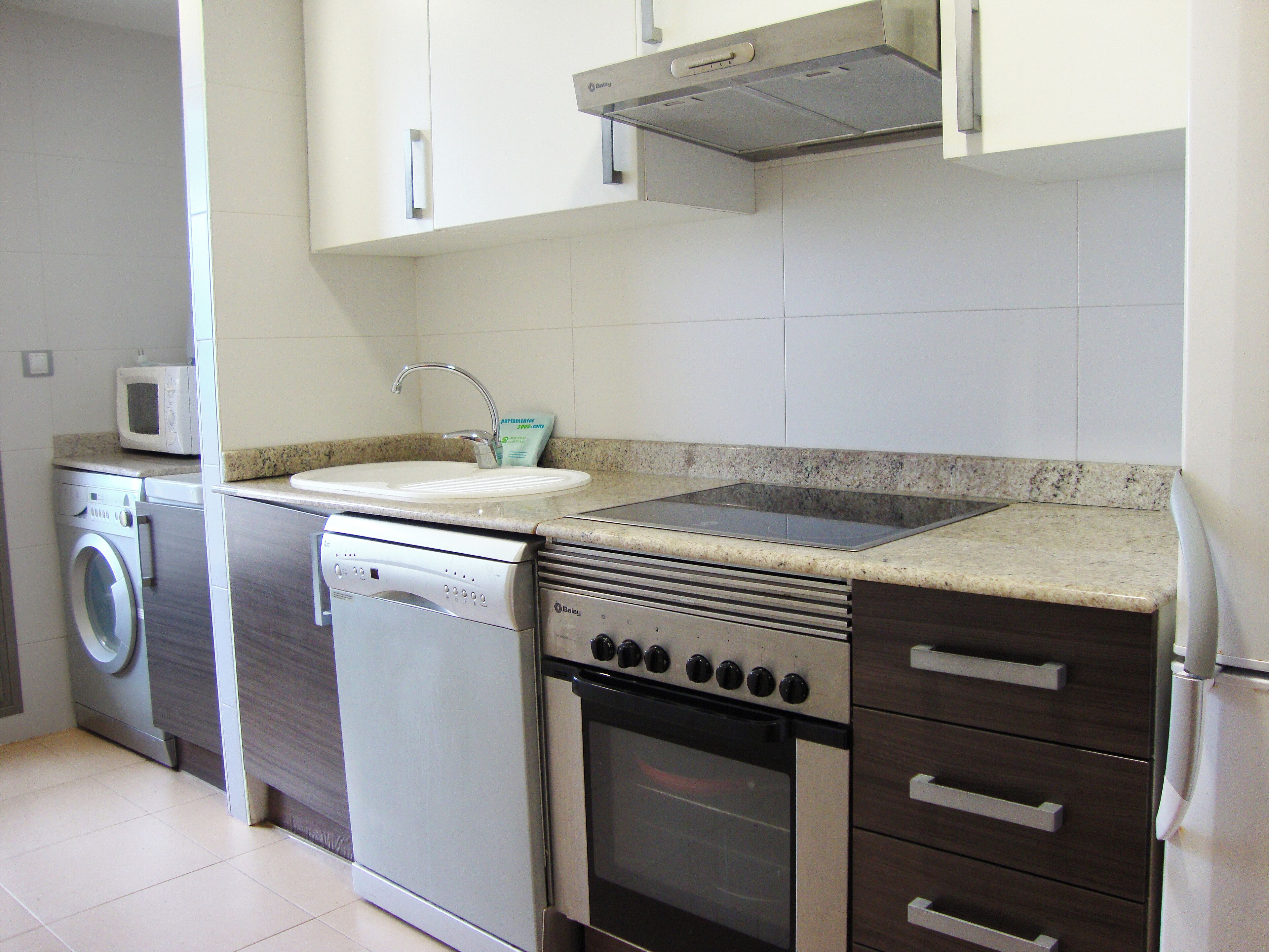 Una cocina compacta equipada con lavavajillas, horno y microondas integrados.
