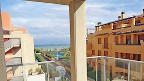 Un balcon avec vue sur la mer, une piscine et les bâtiments avoisinants.