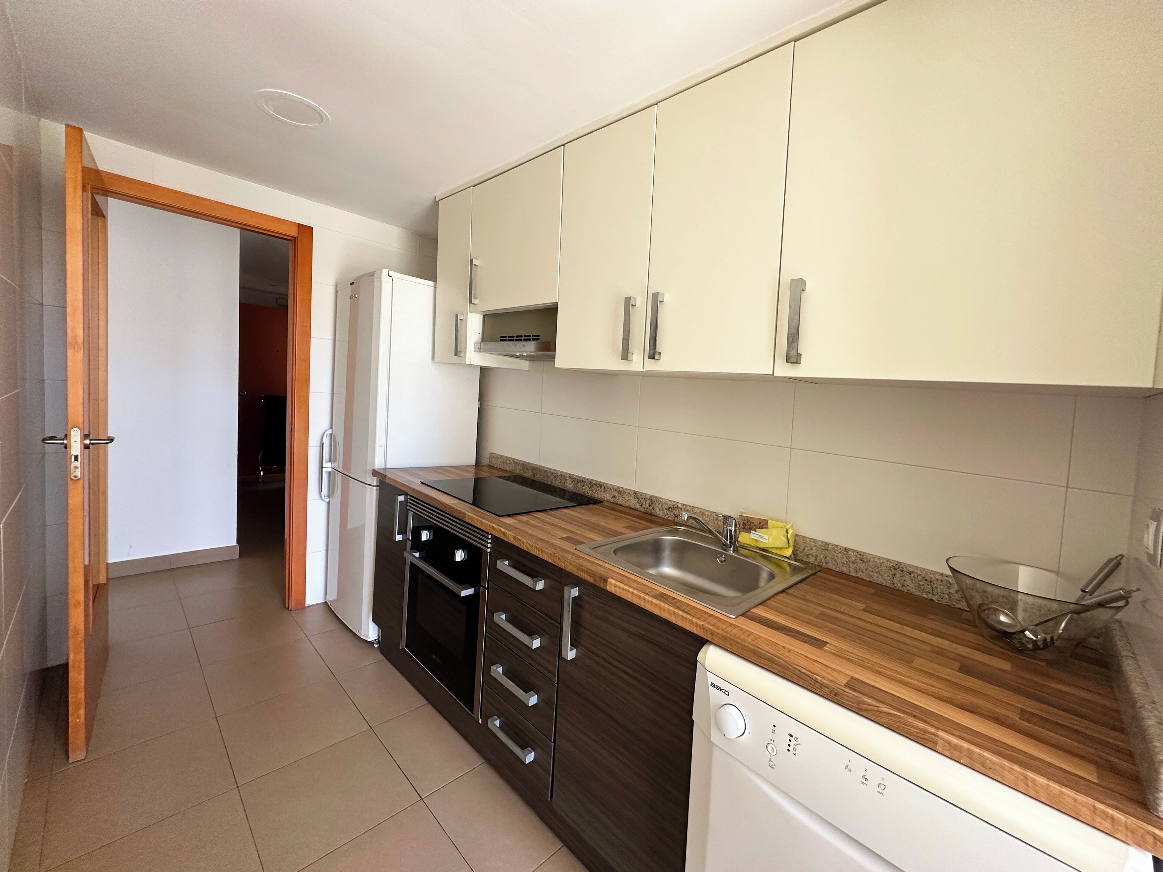 A modern kitchen with white cabinets, a stainless steel sink, and a dishwasher.