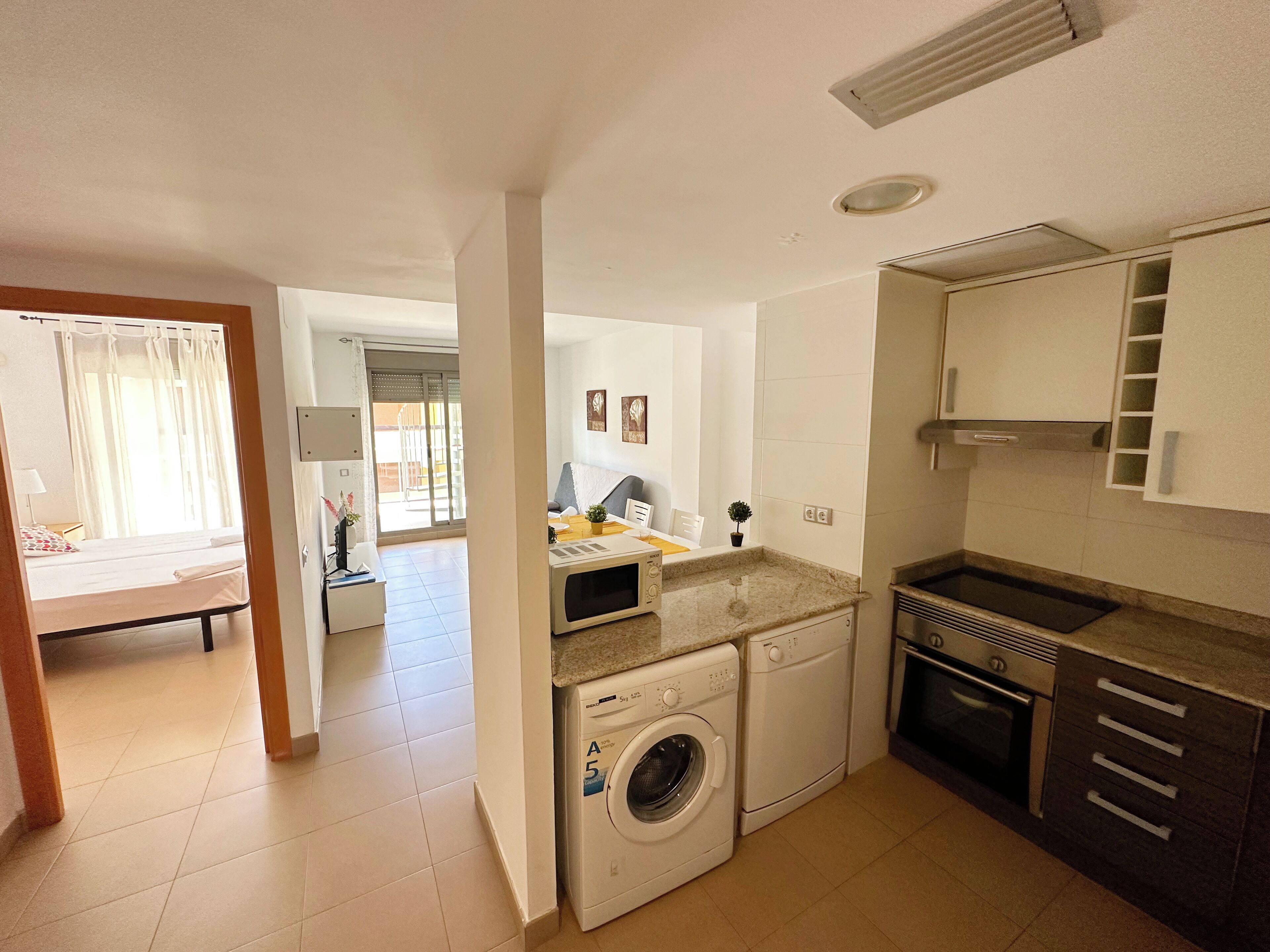 A compact kitchen with a washing machine, a microwave, and a sink.