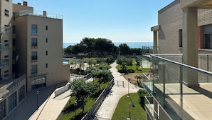 Un hôtel moderne offrant une vue sur la mer, doté d’une cour intérieure agrémentée d’arbres et d’une piscine.