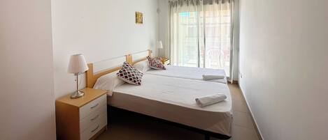 A neatly arranged bedroom with a bed, bedside tables, and a window with curtains.