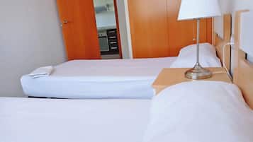 Une chambre d’hôtel avec deux lits, une table de chevet avec une lampe et une armoire.